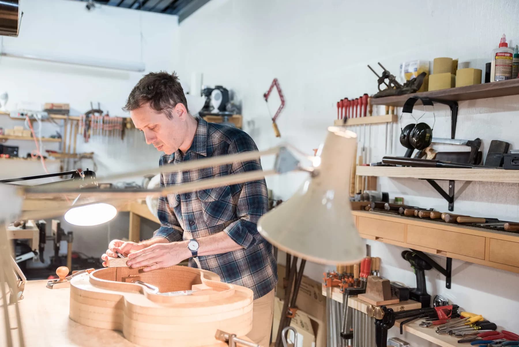 Luthier at the bench shaping a guitar body (placeholder for the engineer’s portrait)